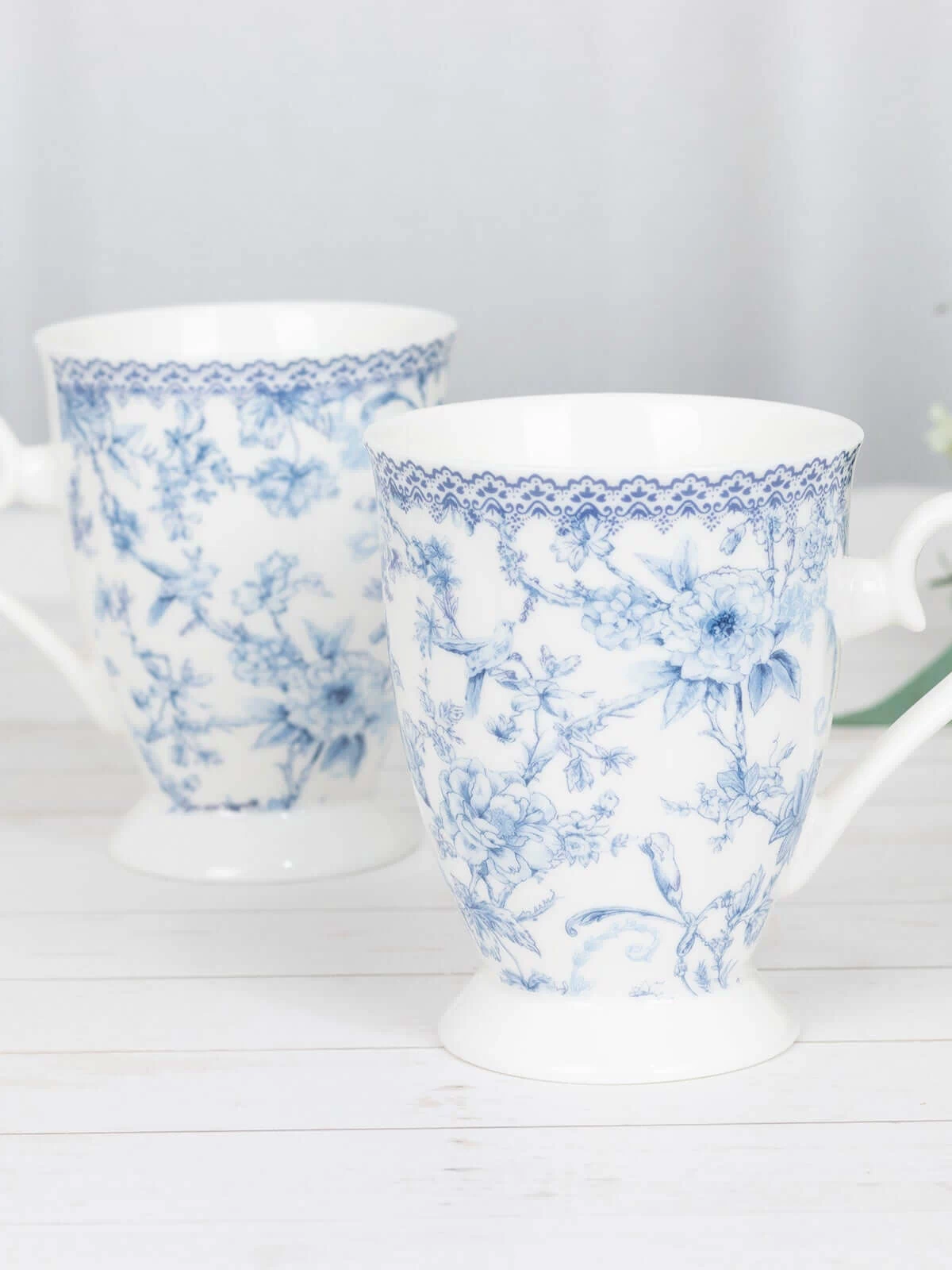 Blue floral patterned ceramic mugs on a light wooden surface.