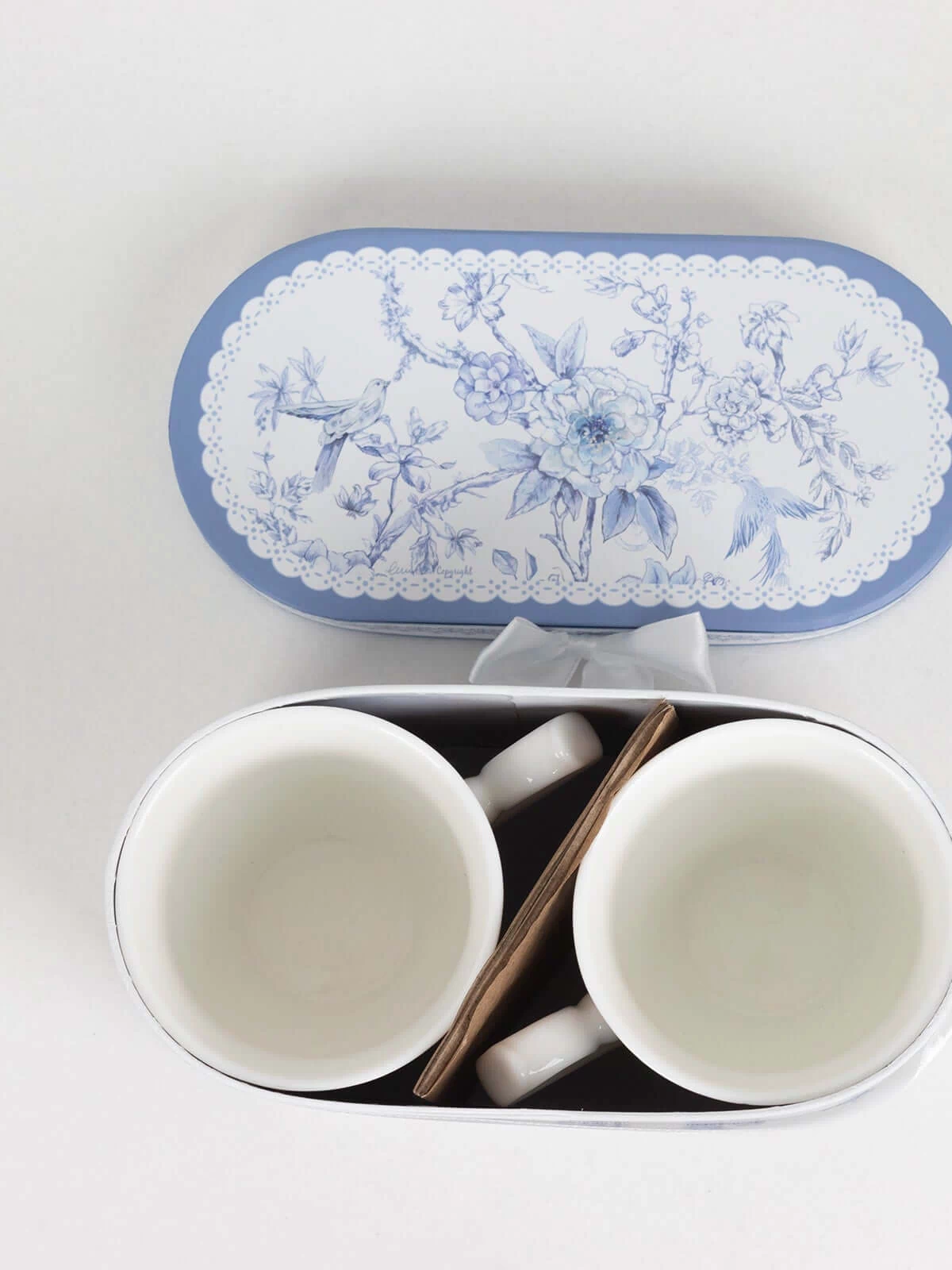 Blue floral ceramic mugs in a decorative tin box.