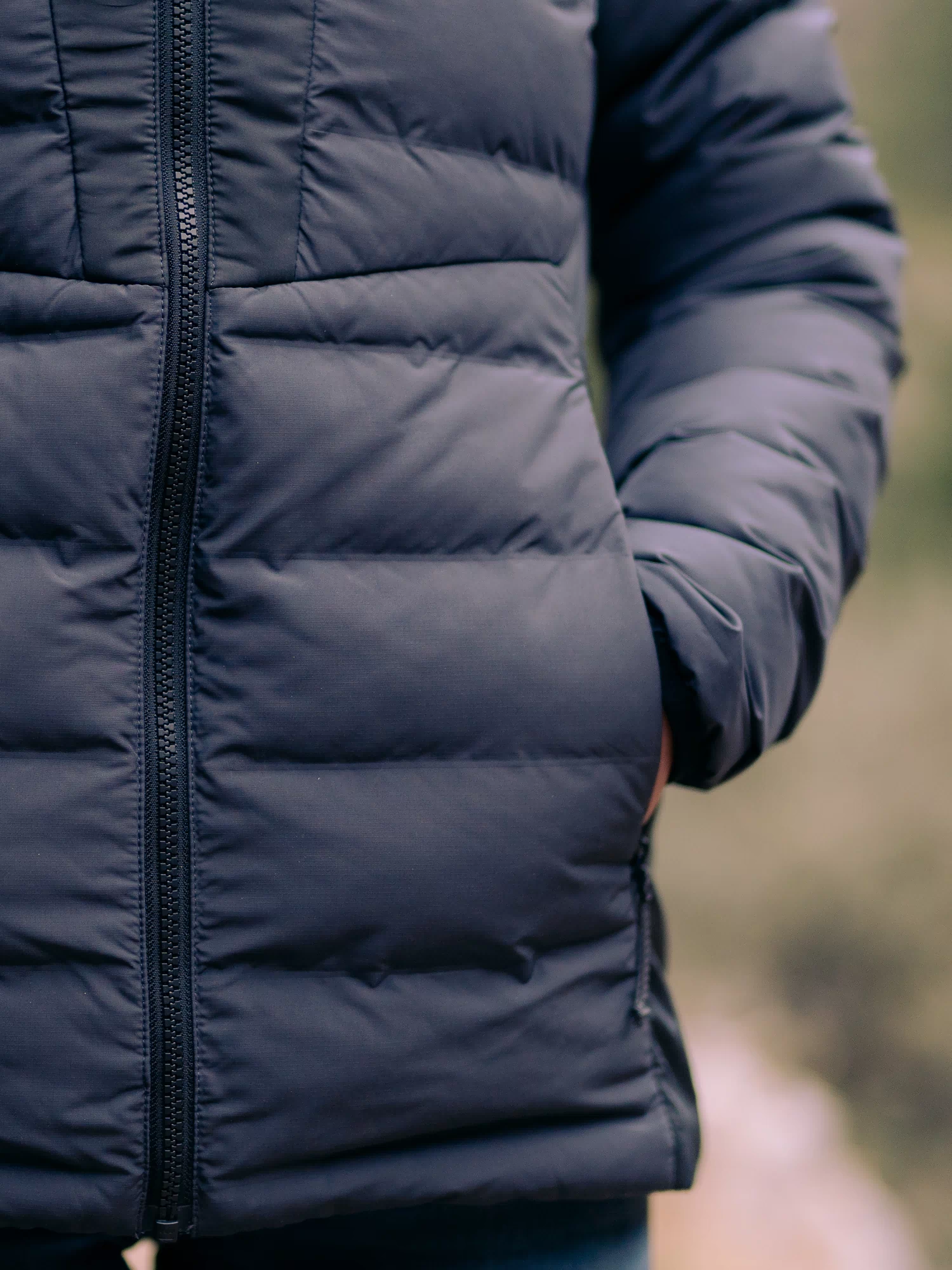 Woman's hand inside zippered hand pockets of the Elements Hooded Jacket in Gunmetal