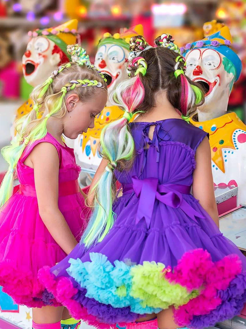 Smiling girl in the limited-edition MADMIA Wonderland Dress featuring pink tulle, colorful frills, and whimsical details.