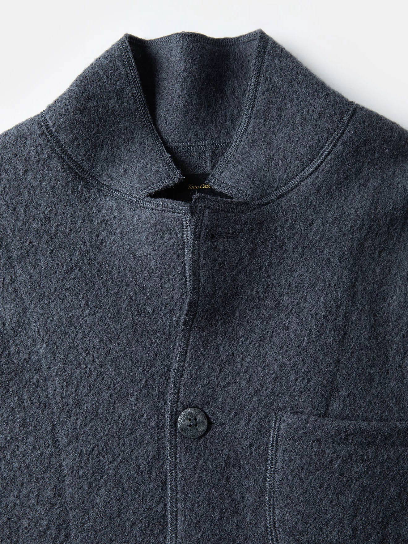 Gray wool felted chore coat close-up with zip front, buttons, and high collar