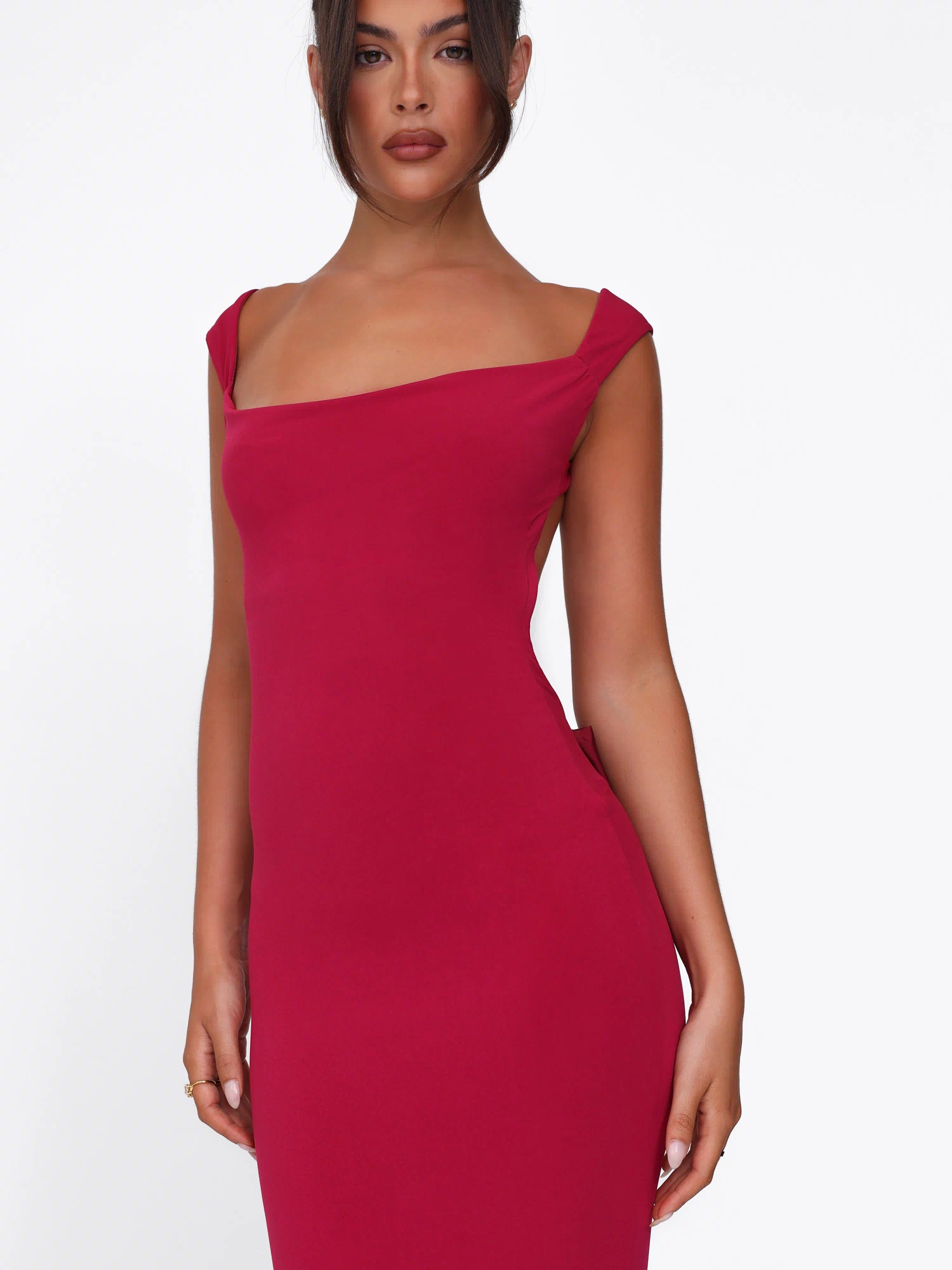A woman wears the TIGERMIST ZITA DRESS in Salsa Deep Red, showcasing a fitted bodycon silhouette with a sleeveless, square neckline design, standing against a plain white background.
